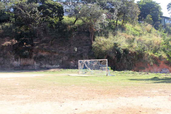 campo de futebol de várzea abandonado, em terra batida. Trave do gol ao centro com rede destruída