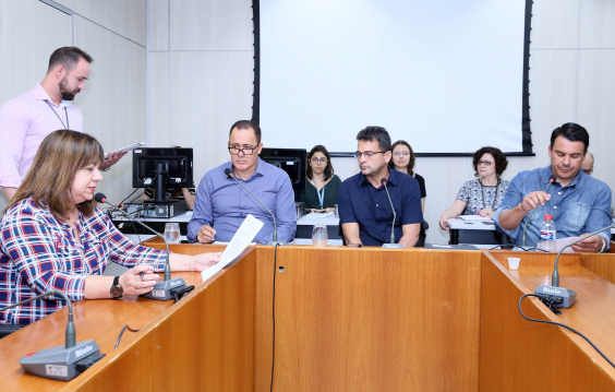 A presidente e outros três integrantes da Comissão de Orçamento e Finanças Públicas estão sentados à Mesa; atrás deles, servidores assessoram a reunião
