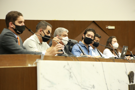 Cinco vereadores e uma vereadora sentados à mesa, portanto máscaras no rosto.
