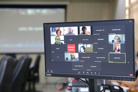 Sete mulheres e um homem dividem tela de computador em reunião remota virtual.