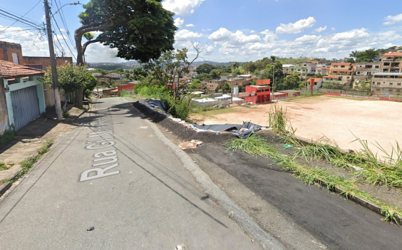Rua residencial à esquerda e campo de futebol à direita, em nível inferior. Entre a rua e o campo, uma área sofreu contenção de desabamento.