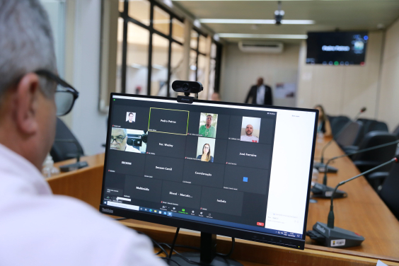 Vereador, sentado à frente de computador, observa a sua imagem e de outros  quatro vereadores em plataforma virtual para reunião remota.
