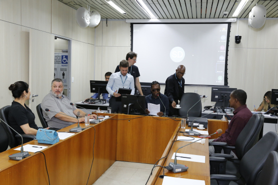 Imagem de vereadores que participam de reunião sentados em uma mesa em U