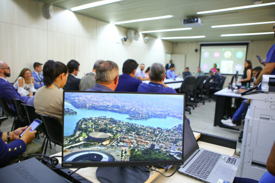 Em primeiro plano, a imagem da lagoa da Pampulha na tela do computador. Ao fundo, a imagem dos participantes da audiência