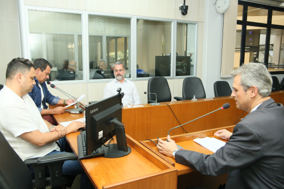Quatro homens reunidos, sentados à mesa