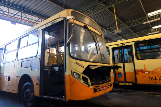Imagem de dois ônibus amarelos com portas abertas e motor à mostra, indicando que estão em manutenção