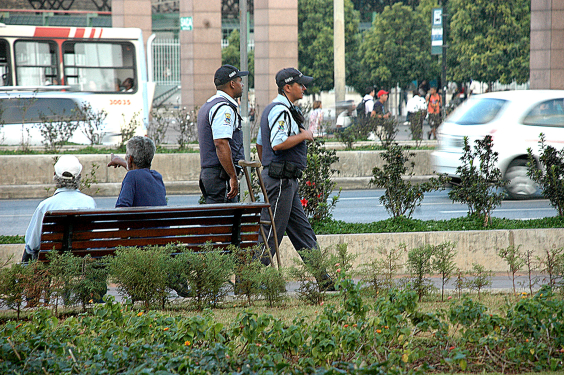 Dois guardas civis municipais caminham em uma praça, durante o dia