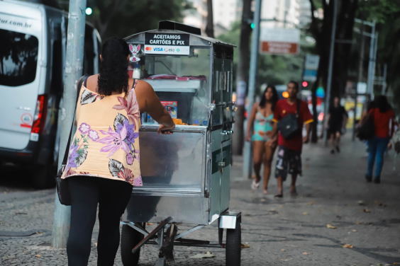 De costas, pipoqueira anda em rua movimentada da cidade, durante o dia