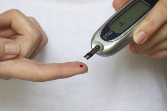 Mãos fazendo teste de glicemia, com furo no dedo indicador