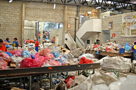 Imagem mostra montanhas de lixo reciclável e alguns catadores