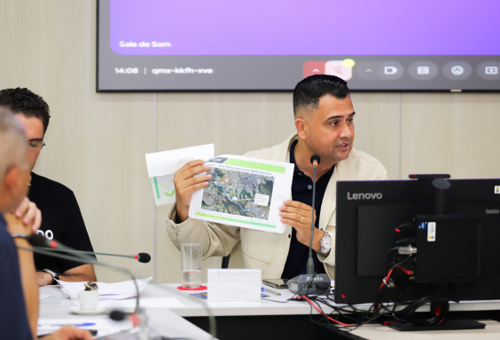 Vereador Irlan Melo segura uma folha com uma foto do Anel Rodoviário.