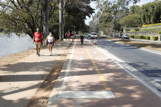trecho da avenida Otacílio Negrão de Lima, na orla da Lagoa da Pampulha, mostrando pedestres, motoristas e ciclistas