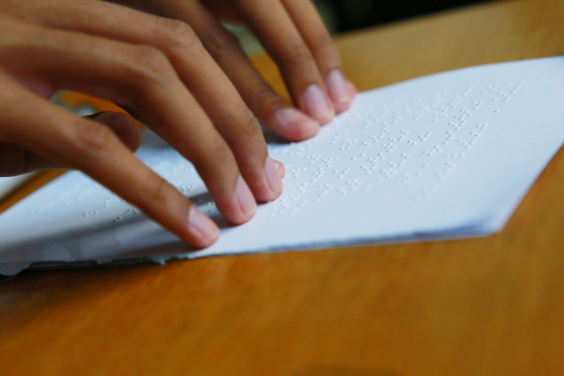 pessoa faz leitura de documento em braille