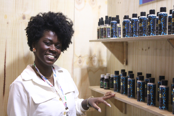 mulher negra ao lado de estanto com produtos cosméticos