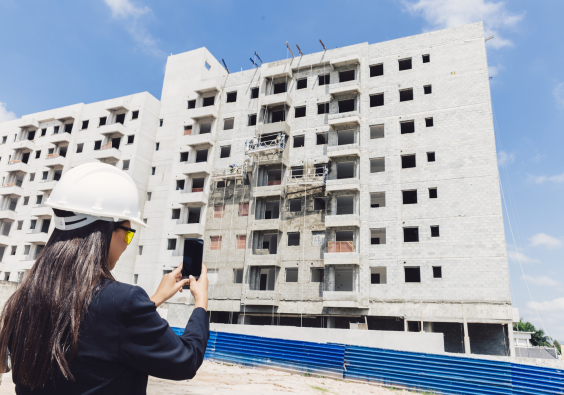 mulher com capacete fotografa prédio em construção
