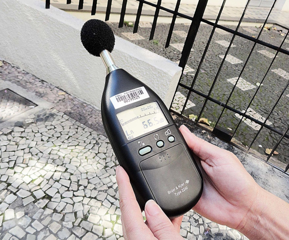 mãos segurando um aparelho medidor de nível sonoro