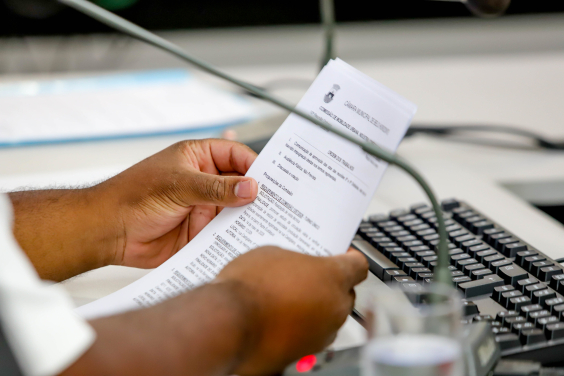 Mão de vereador segurando requerimento de comissão