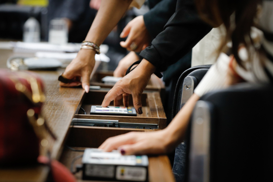 mãos de parlametar operando terminal de votação