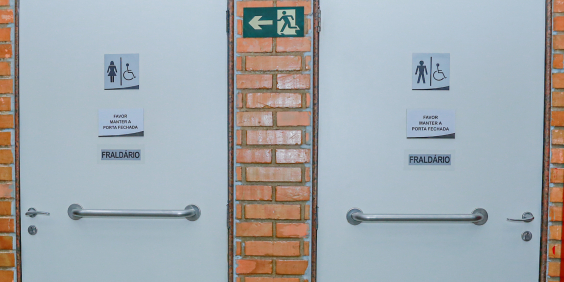 Imagem de duas portas com a identificação da figura de uma mulher e de um homem. Cada porta também traz a informação de cadeirante e fraldário