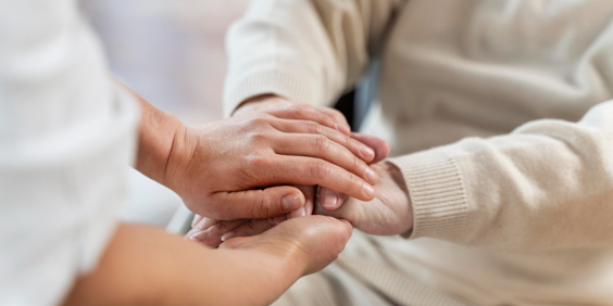 Mãos de pessoa jovem segurando mãos de idosa