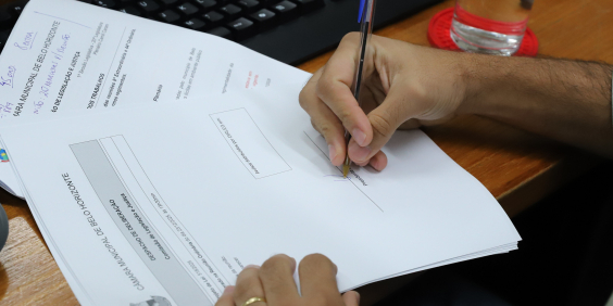 Vereador assina documento durante reunião da comissão de legislação e justiça da CMBH