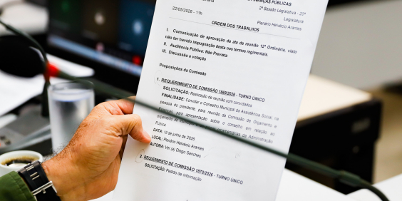 Mão de vereador segura pauta durante reunião da comissão