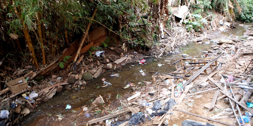 Córrego assoreado, sujo, poluído, com entulhos e dejetos de todo tipo