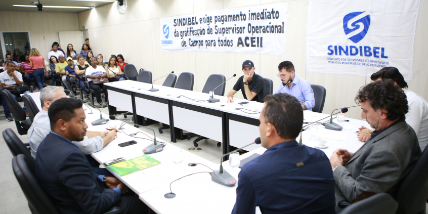A imagem mostra o vereador Gilson Reis e demais componentes da Mesa. Ao fundo, nas cadeiras, os ACEs II presentes no Plenário 