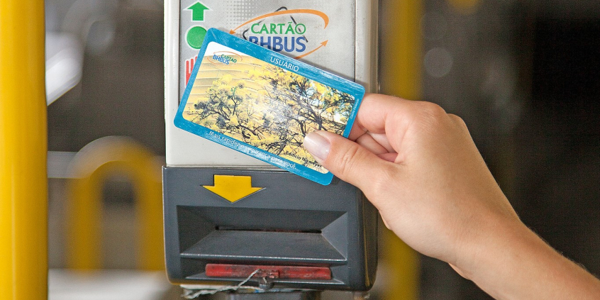 detalhe de uma mão segurando o cartão bhbus em frente ao sensor, na catraca do ônibus
