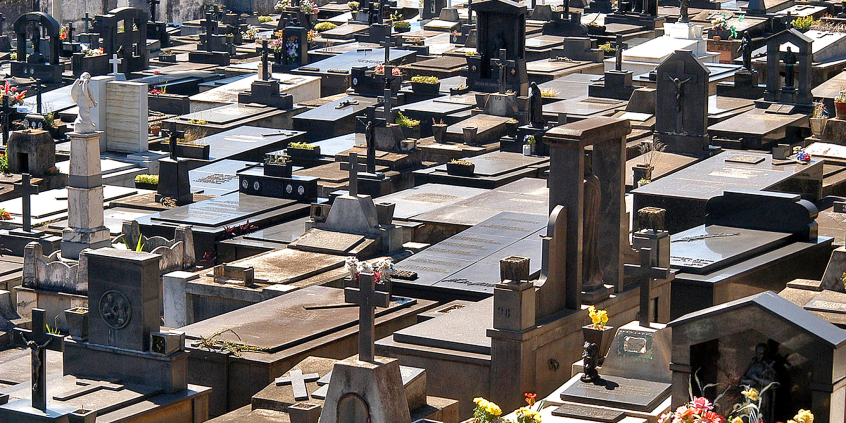 Mais de trinta túmulos em cemitério municipal, durante o dia.