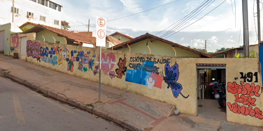 Fachada do Centro de Saúde Campo Alegre, com borboletas, coração e outras imagens coloridas pintadas em muro amarelo, durante o dia.