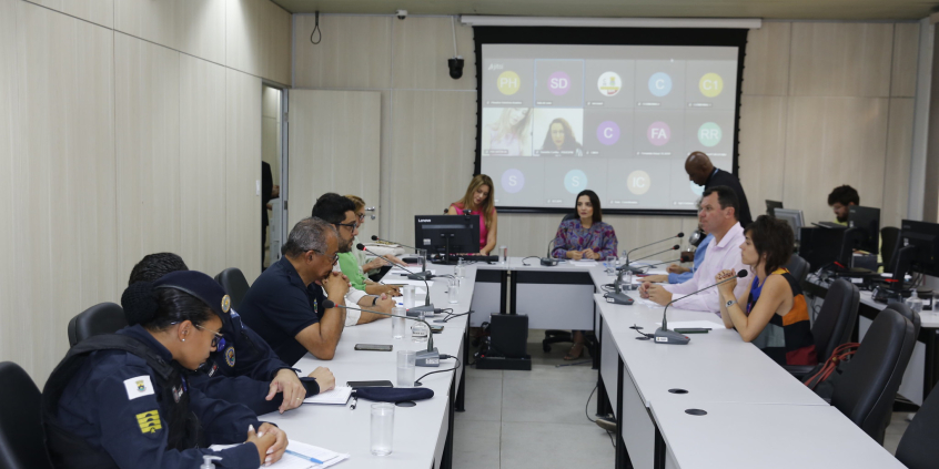 Seis mulheres e quatro homens participam de reunião sentados à mesa