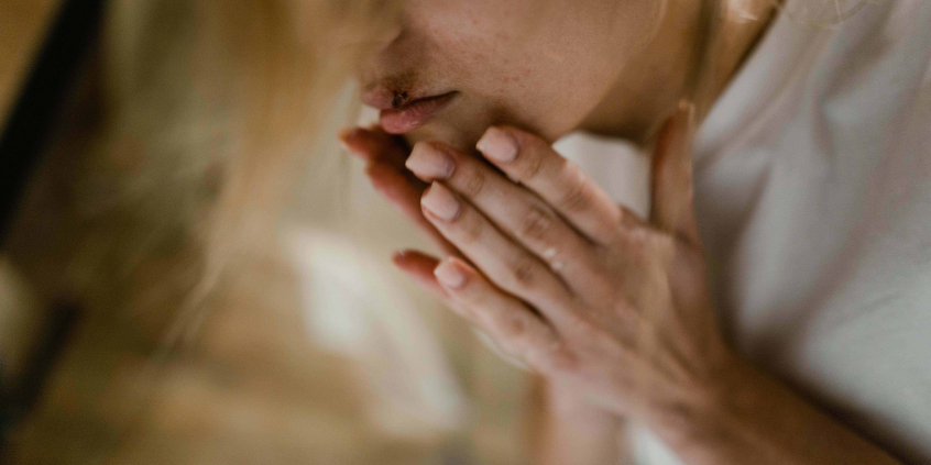 Foto mostra parte do rosto e mãos de uma mulher