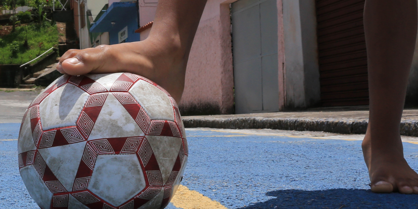 pés infantis jogando bola em rua de bairro, durante o dia