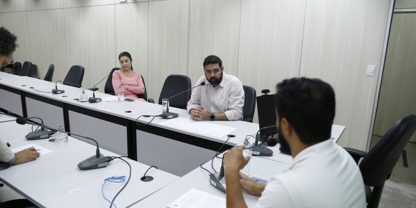 Três vereadores reunidos, sentados à mesa. 