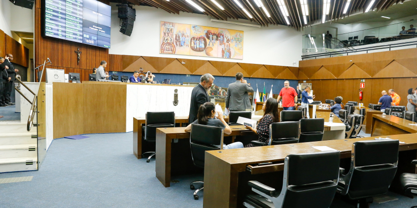 imagem do Plenário Amynthas de Barros. Ao fundo, a mesa diretora e em primeiro plano as cadeiras dos parlamentares
