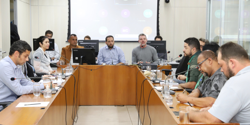Quatro parlamentares e seis cidadãos e representantes do Município e de empresa, sentados à mesa, em reunião