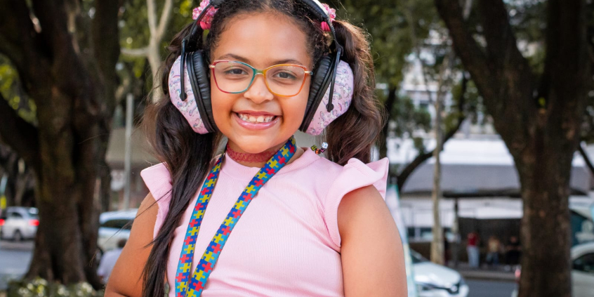 Menina com fone de ouvido e crachá de TEA