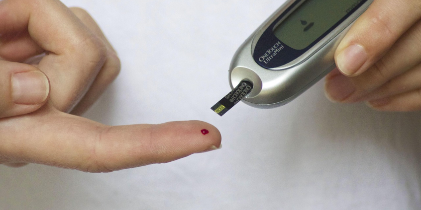 Mãos fazendo teste de glicemia, com furo no dedo indicador