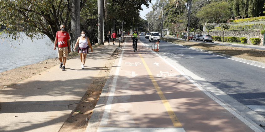 trecho da avenida Otacílio Negrão de Lima, na orla da Lagoa da Pampulha, mostrando pedestres, motoristas e ciclistas