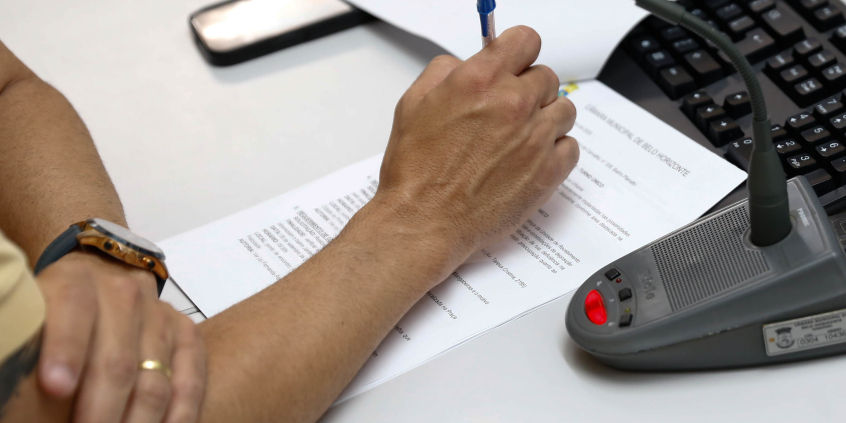 close em mãos segurando caneta em cima de documento de papel