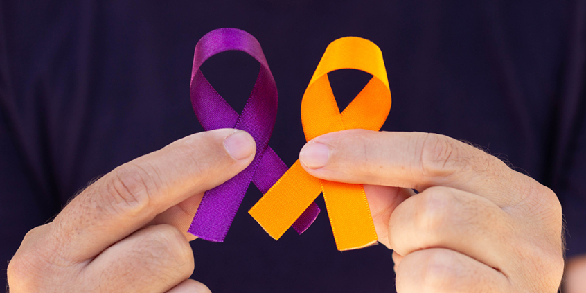 close nas mãos de pessoa segurando laços nas cores roxo e laranja