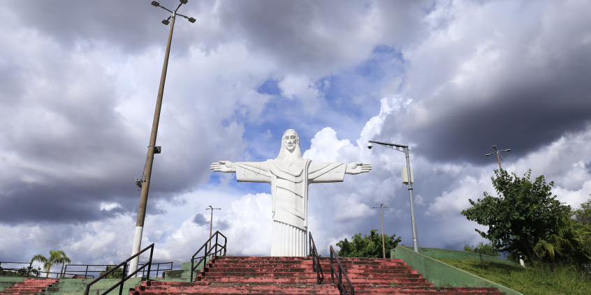Imagem do Cristo do Barreiro no alto de uma escadaria. Ao fundo, o céu está nublado