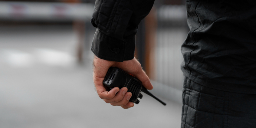 close nas mãos de homem uniformizado segurando um rádio comunicador