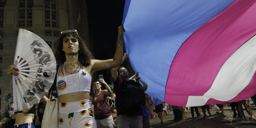 Pessoas levantam bandeira trans