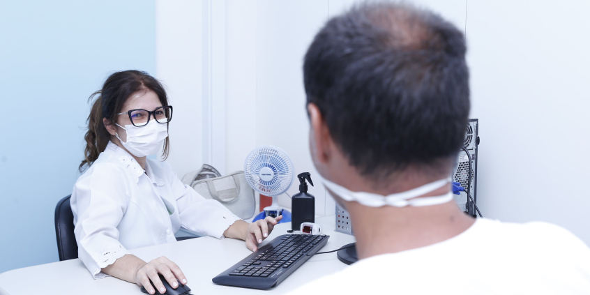 Médica de máscara atende paciente em centro de saúde de BH