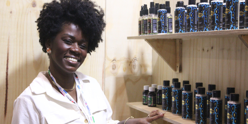 mulher negra ao lado de estanto com produtos cosméticos