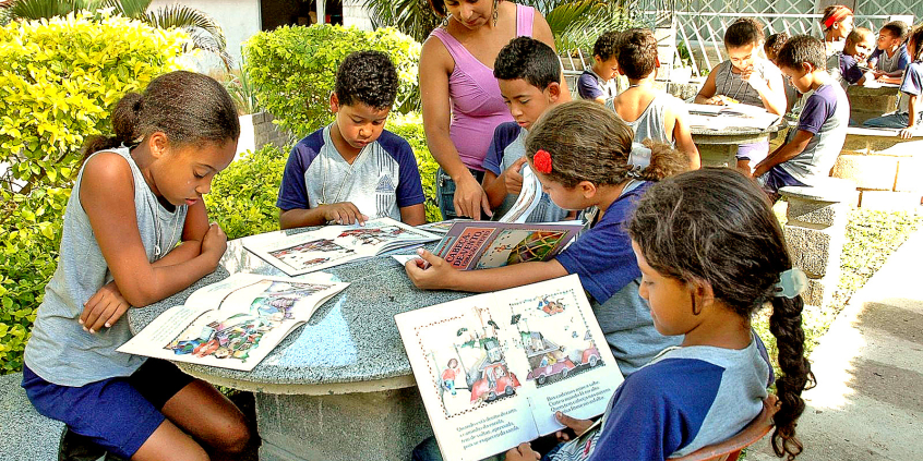 profissional de educação auxilia estudantes durante leitura de livro