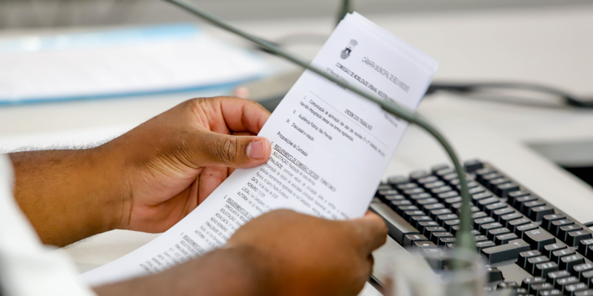 Mão de vereador segurando requerimento de comissão