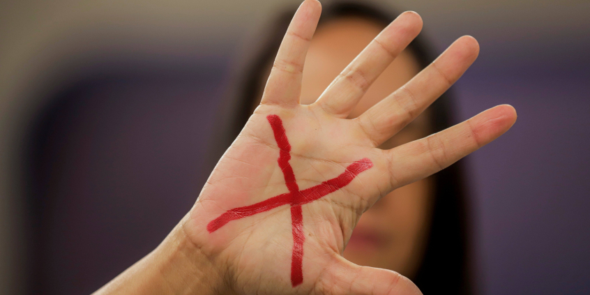 Mão de mulher com um X em vermelho